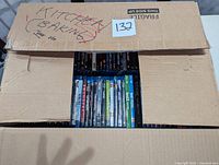 Box partially open showing rows of mixed Blu-ray and DVD movies in cases, label on box says KITCHEN BAKING