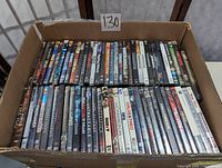 Top view of a cardboard box filled with assorted DVDs showing various titles