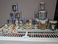 Photo of assorted Precious Moments figurines and ornaments, some boxed, arranged on wire shelf