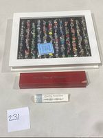 Wooden display case with 12 monthly themed charm bracelets visible through glass top, red 12 Days of Christmas box, and Quality Assurance packet shown on flat surface.