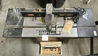 Top view of full Craftsman router table with mounted router, bits in box on table, and additional packaged parts.