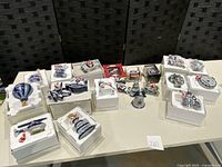 Photo of 21 Dallas Cowboys Christmas ornaments laid out on a table, showing variety and packaging.