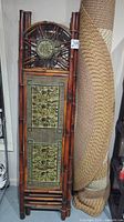 Full view of folded bamboo room divider next to rolled braided rug.
