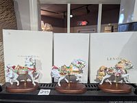 Three Lenox carousel horse figurines on wood bases with original boxes behind them.