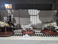 Full lot showing three of the four Lenox carousel horses against their original packaging boxes, positioned on wooden bases with metal poles.