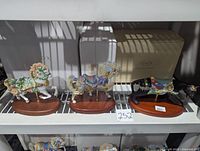Lot of three Lenox collectable carousel figures displayed on metal shelf with boxes in background