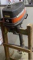 Full side view of Mariner 4HP outboard engine mounted on wooden stand, showing overall size and design
