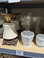 Photo of two untested electric milk glass hurricane lamps with hobnail pattern, metal filigree bases, and two clear glass chimney globes, along with two milk glass vases.