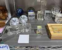 Glass paperweight collection showing varied shapes and designs including Texas Stadium and etched cubes.