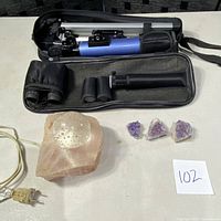 Full view of telescope with tripod and accessories, Himalayan salt lamp, and three amethyst geodes on table.