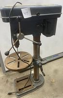 Front view of the full drill press showing handle, worktable, base and power cord.