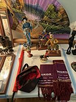 Wide view of the collection showing fans, dolls, textiles, and small sculptures arranged on a table.