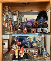 Shelf displaying a variety of Asian inspired figurines, samurai miniatures, fans and decorative items