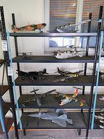 Multiple shelves with assorted model airplanes of various styles, sizes, and colors including military and commercial aircraft.