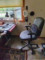 Room view showing black office chair next to desk with two lamps attached near a window