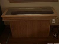 Front view of light wood display case with glass top showcasing a rectangular design and rounded edges.