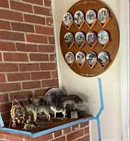 Photo showing the full set of wolf-themed items including the wall plaque with 12 plates, three wolf figurines on a shelf below, and a wolf face dreamcatcher hanging to the side.