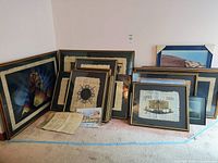 Photo showing a collection of framed papyrus artworks leaning against the wall, featuring Egyptian themes in wood frames with black and gold coloring.