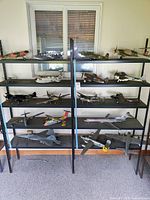 Front view of black metal display shelves showing multiple tiers and visible rust on brackets, shelves holding various airplane models.