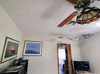 Wide angle showing multiple model aircraft suspended from ceiling, framed aviation and naval wall art on walls, and model ships on cabinet below.