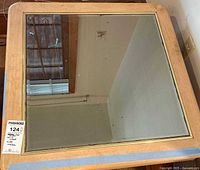 Top view of square coffee table showing glass inset and light wood frame with wave pattern trim.