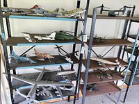 Wide view of two black metal shelving units holding multiple assembled military aircraft models in various sizes and colors.