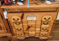 Front view of traditional natural wood dresser showing four drawers and decorative carved detailing along top and drawer fronts.