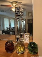 Image showing the full set of glassware including Galileo thermometer and three glass paperweights on a wooden surface with mirror background.