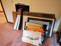 Stack of various framed and unframed vintage U.S. Air Force plane prints and photos on floor