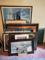 Various framed historical U.S. Navy prints depicting ships, submarines, and aircraft arranged together with visible wear on one frame.
