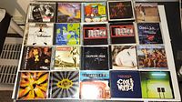 Top view of 20 music CD cases featuring various artists and albums, mostly rock and pop from 1990s and 2000s.