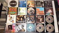 Photo showing 20 music CDs laid out on a table with visible covers including Third Eye Blind, Old 97's, and world music compilations