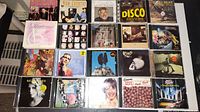 Image showing 25 CD jewel cases arranged in rows, featuring album covers with different artists and designs.