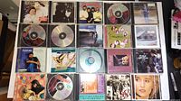 Photo of 20 various music CDs in jewel cases and disc-only showing front covers and discs