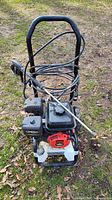 Full front view of the Briggs & Stratton gas-powered pressure washer with hose wound around the handle, placed outside on grass with leaves.