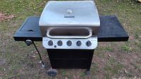 Full front view of the Char-Broil grill showing lid, control panel, and side shelves on grass.