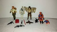 Four 1980s GI Joe action figures with their respective accessories laid out in front of a white background.