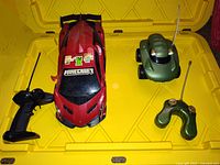 Red sports car with Minecraft stickers and black remote control in yellow plastic bin.