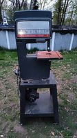 Side angle of the vintage Sears Craftsman band saw sander machinery and stand showing the work table and base storage shelf.