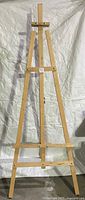 Full view of the wooden tripod easel stand showing overall shape and structure.