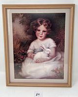 Signed print of child with white rabbit, framed in a wooden frame with minor wear.