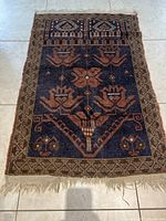 Full view of the antique Kuba wool rug showing geometric floral patterns and blue background.