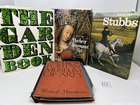 Four hardcover art books displayed on a white surface. Titles visible: 'The Garden Book', 'Northern Renaissance Art', 'Stubbs', and 'Album of Miniatures'. Covers show botanical, Renaissance portrait, equestrian painting, and text designs respectively.