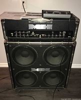 Amp head stacked on matching 4×12 cabinet with footswitch on top