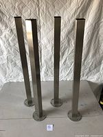 Four square metal legs standing upright on a surface, showing overall condition and design.