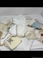 Assortment of white and pastel handkerchiefs and napkins with lace and embroidery seen spread out