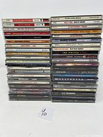 Photo showing overall collection of 44 CD albums stacked in two columns, with visible titles and artists on spines for verification of lot contents.