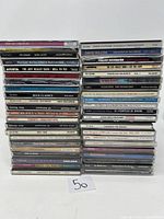 Front view of stacked CDs showing spines with artist names and album titles.