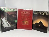 Front view of three hardcover books: "Canada Across the Land" with waterfall cover, "Pictorial Atlas of the World" with red cover and world map embossing, and "The Horizon Book of Lost Worlds" with a pyramid and night sky cover