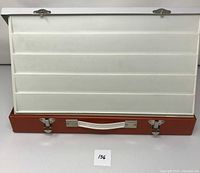 Front view of the open slide viewer case, showing multiple horizontal slots for slides and two metal latches on the outside perimeter.